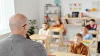 Male teacher in classroom with learners